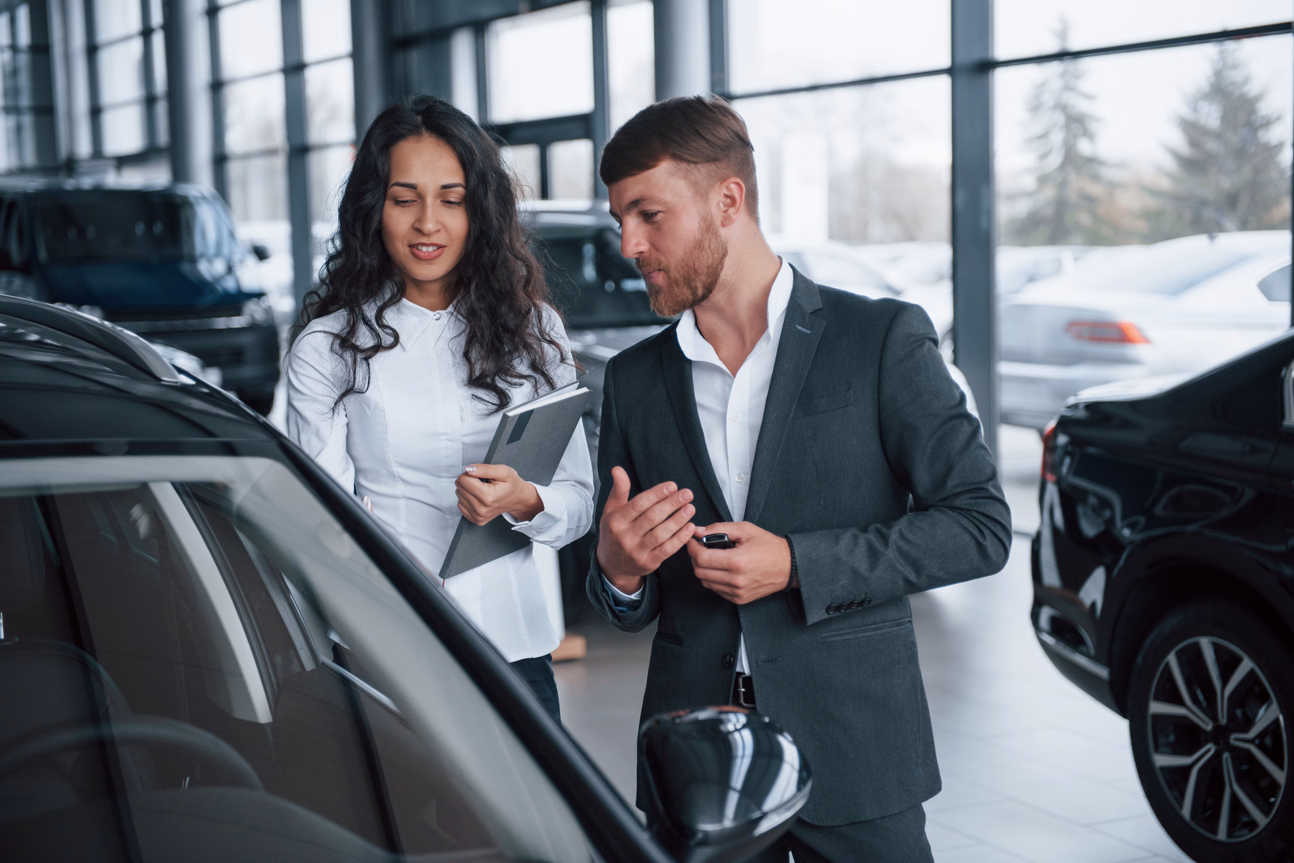 I'm very impressed about that new vehicle. Female customer and modern stylish bearded businessman in the automobile saloon Specialized Services for Automotive Businesses